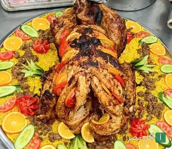 طبق كبير من الأرز الأصفر مع دجاج مشوي مزين بشرائح البرتقال والطماطم والخيار في مطعم عبد الباسط عبد الصمد بعين شمس.