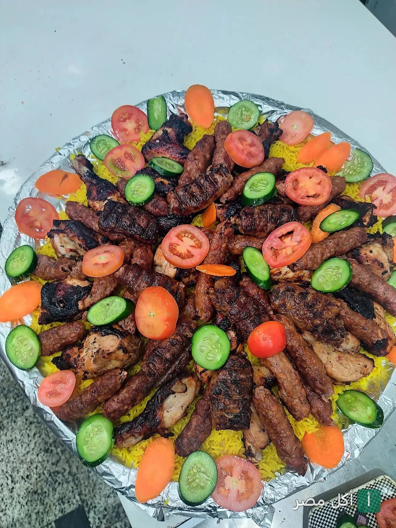 طبق مشويات مشكل من مطعم عبد الباسط عبد الصمد في عين شمس، يقدم مع أرز أصفر وخضروات طازجة.