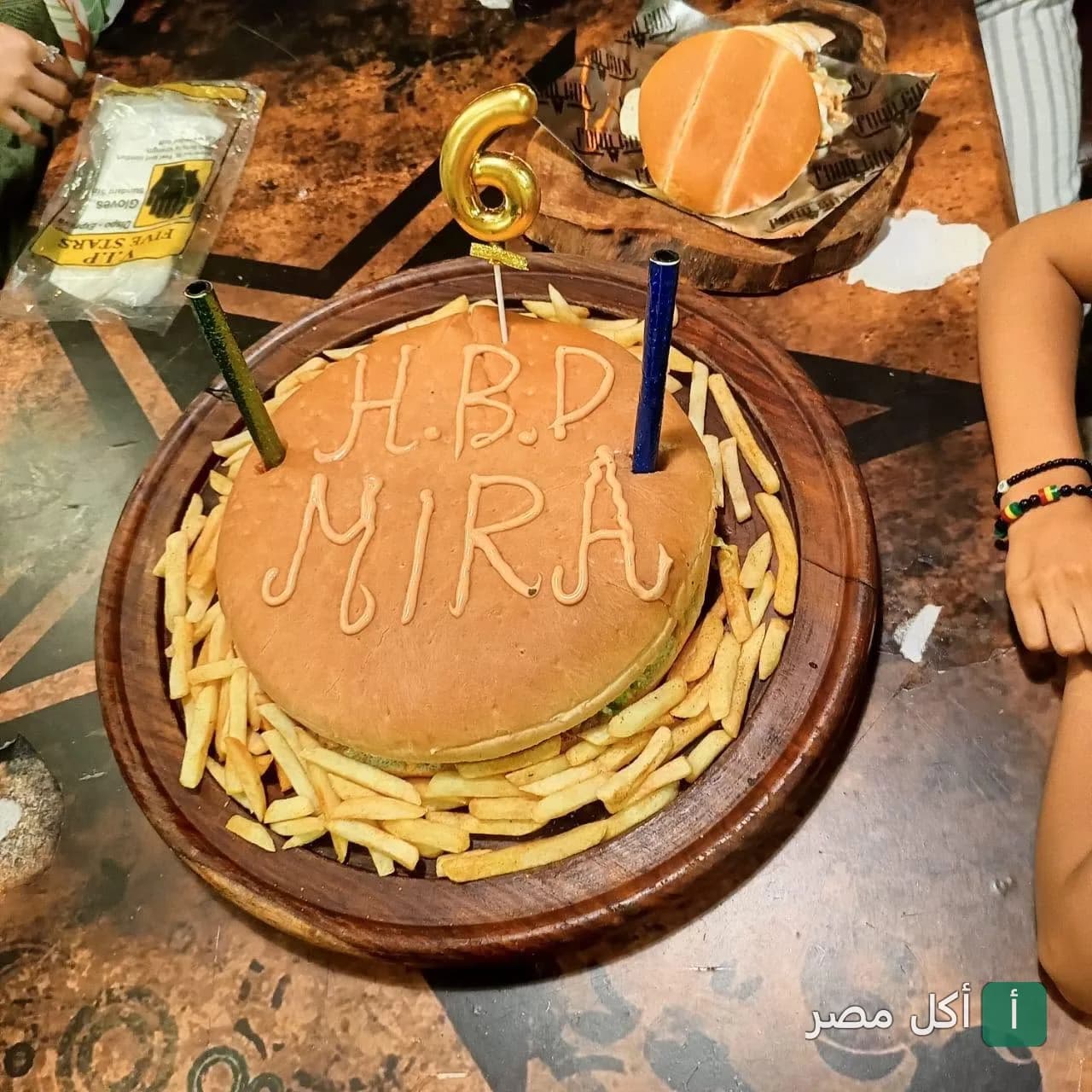 برجر عيد ميلاد كبير مكتوب عليه H.B.D MIRA مع بطاطس مقلية في مطعم فود جن بعين شمس.