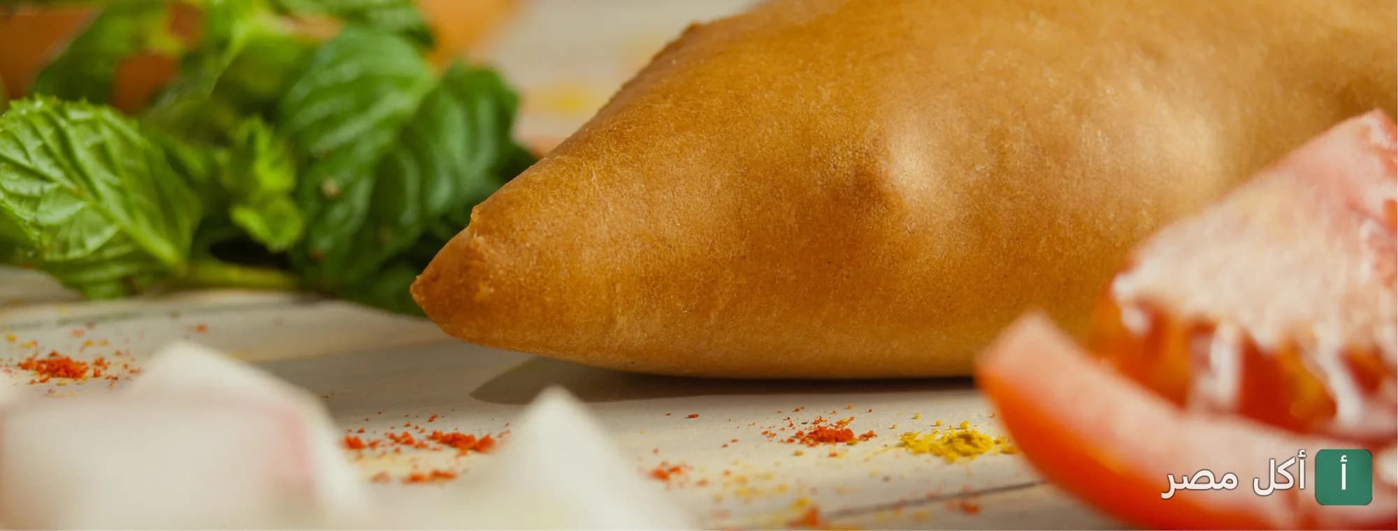 فطيرة ذهبية مخبوزة بجانبها طماطم ونعناع طازج في مطعم الطيب بعين شمس.