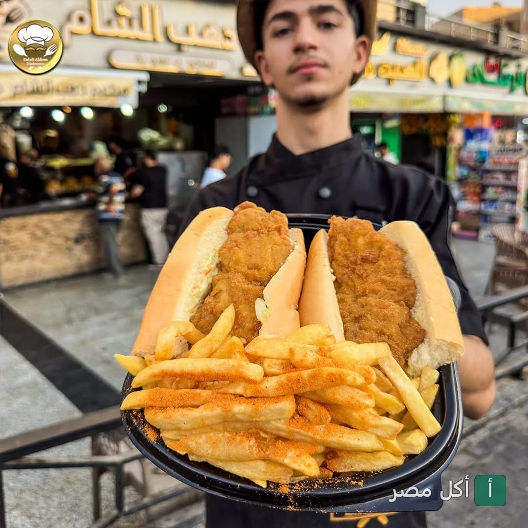 موظف مطعم دهب الشام في عين شمس يقدم وجبة ساندوتشات بانيه مع بطاطس مقلية.