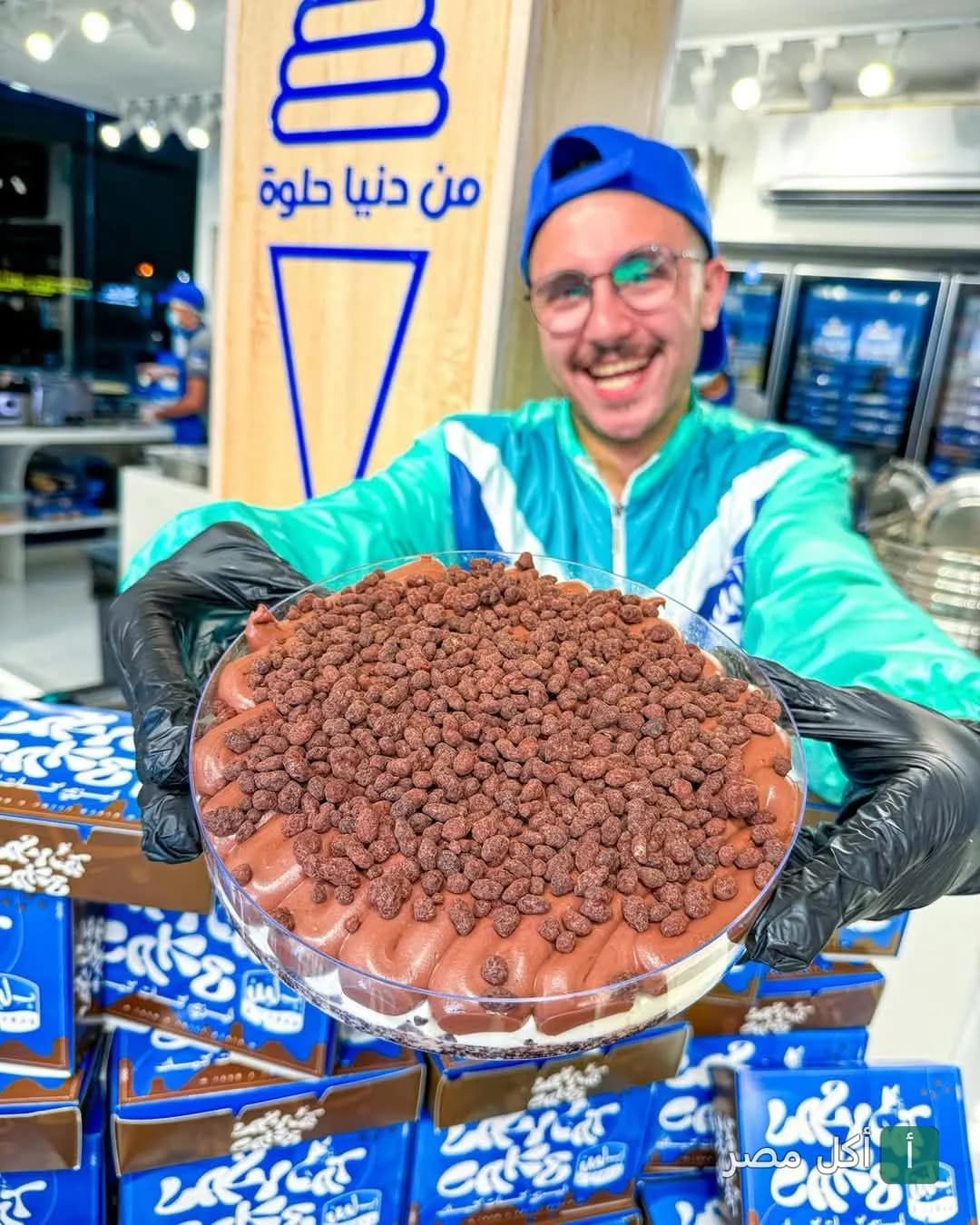 موظف بـ لبن يقدم علبة حلوى بالشوكولاتة مغطاة بحبيبات مقرمشة في فرع عين شمس.