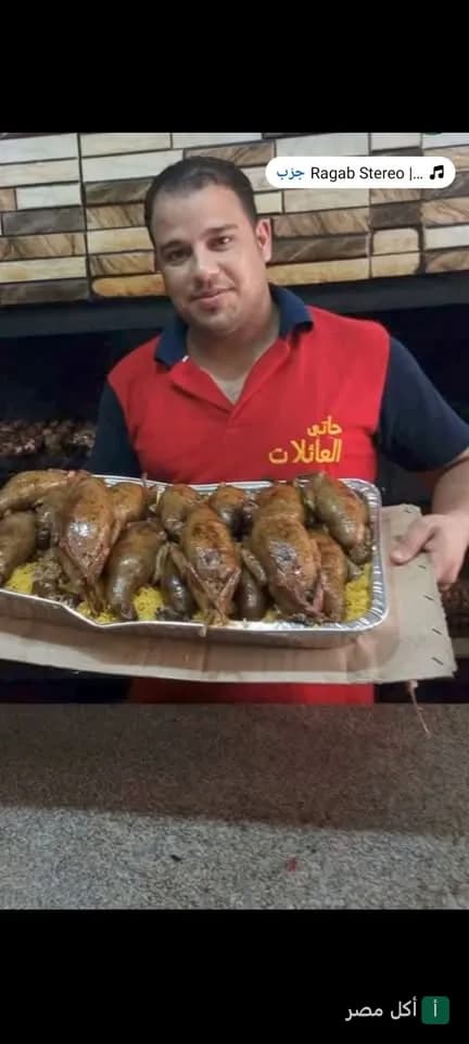موظف في حاتي العائلات بعين شمس يحمل صينية كبيرة من الحمام المحشي.