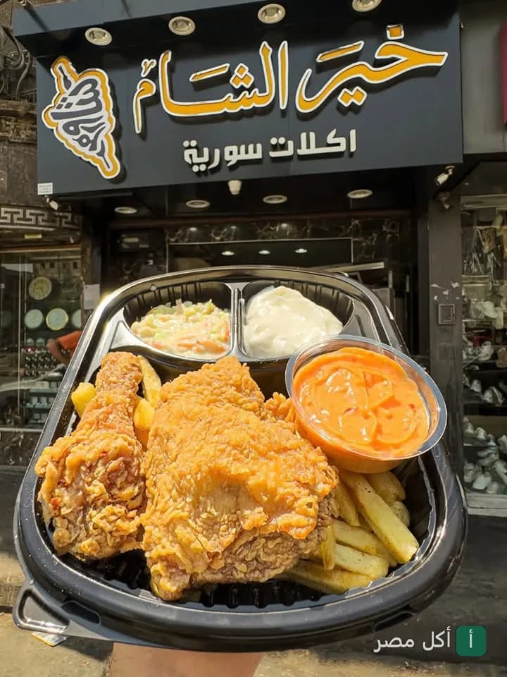 وجبة دجاج مقلي مع بطاطس وصوصات أمام واجهة مطعم خير الشام في عين شمس.