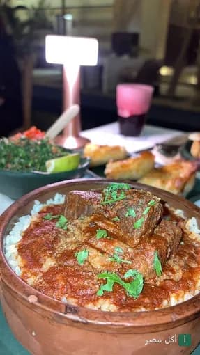 طاجن لحم بالأرز في مطعم جرانيتا بمنطقة الأزهر، مع طبق جانبي ومشروب على طاولة الطعام.