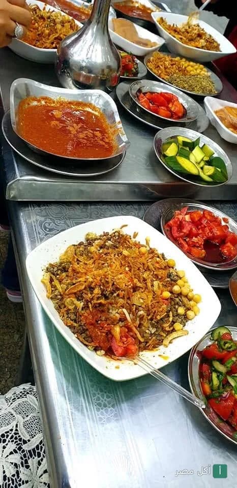 أطباق كشري مصري متنوعة مع صلصة ومقبلات على طاولة في مطعم كشري وطواجن السلطان حسن بالدرب الأحمر.