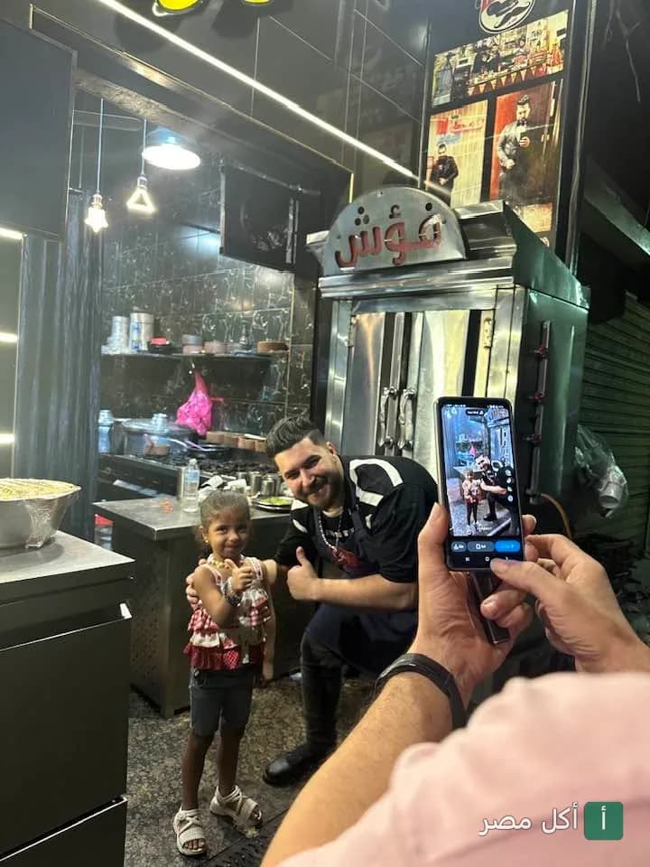شيف مطعم فؤش ابن سيد في حوش قدم يلتقط صورة مع طفلة أمام ماكينة الشاورما.