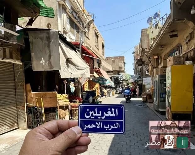 يد تحمل لافتة شارع المغربلين في منطقة الدرب الأحمر بالقاهرة أمام مطعم كشري المؤمن.