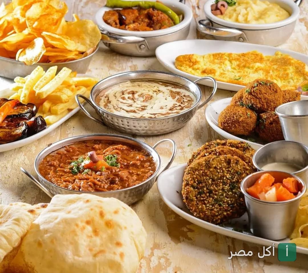 سفرة فطار مصري متنوعة من مطعم عم سيد في الخليفة تضم فول وطعمية وبطاطس مقلية وأومليت.
