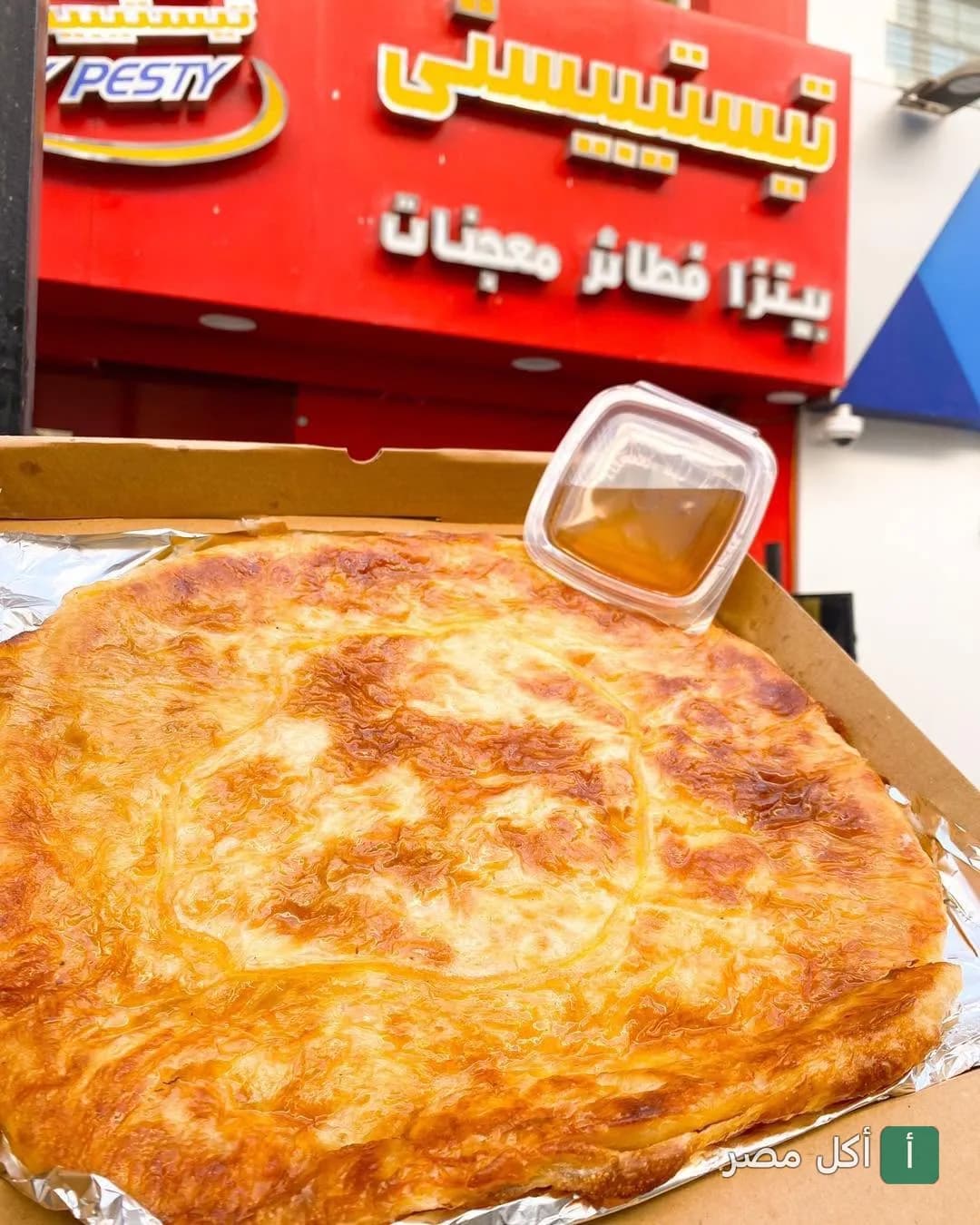 فطيرة شرقية في علبة كرتون أمام واجهة مطعم تيستيبيستي في الجيزة.