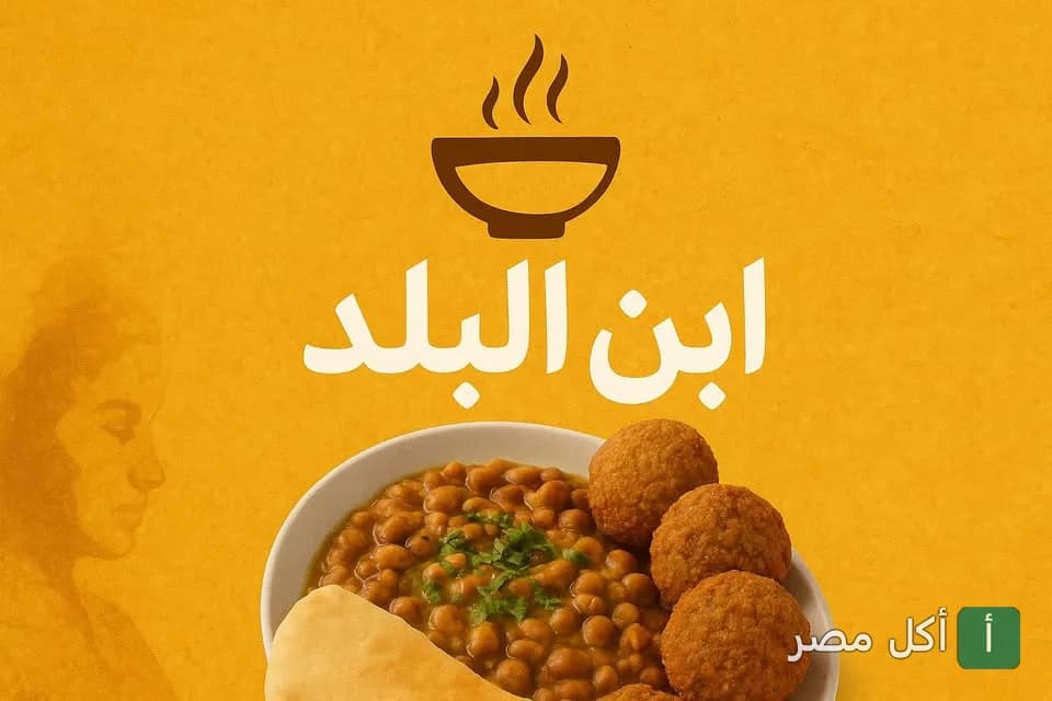 طبق فول وطعمية على خلفية صفراء بشعار مطعم ابن البلد في الخليفة.