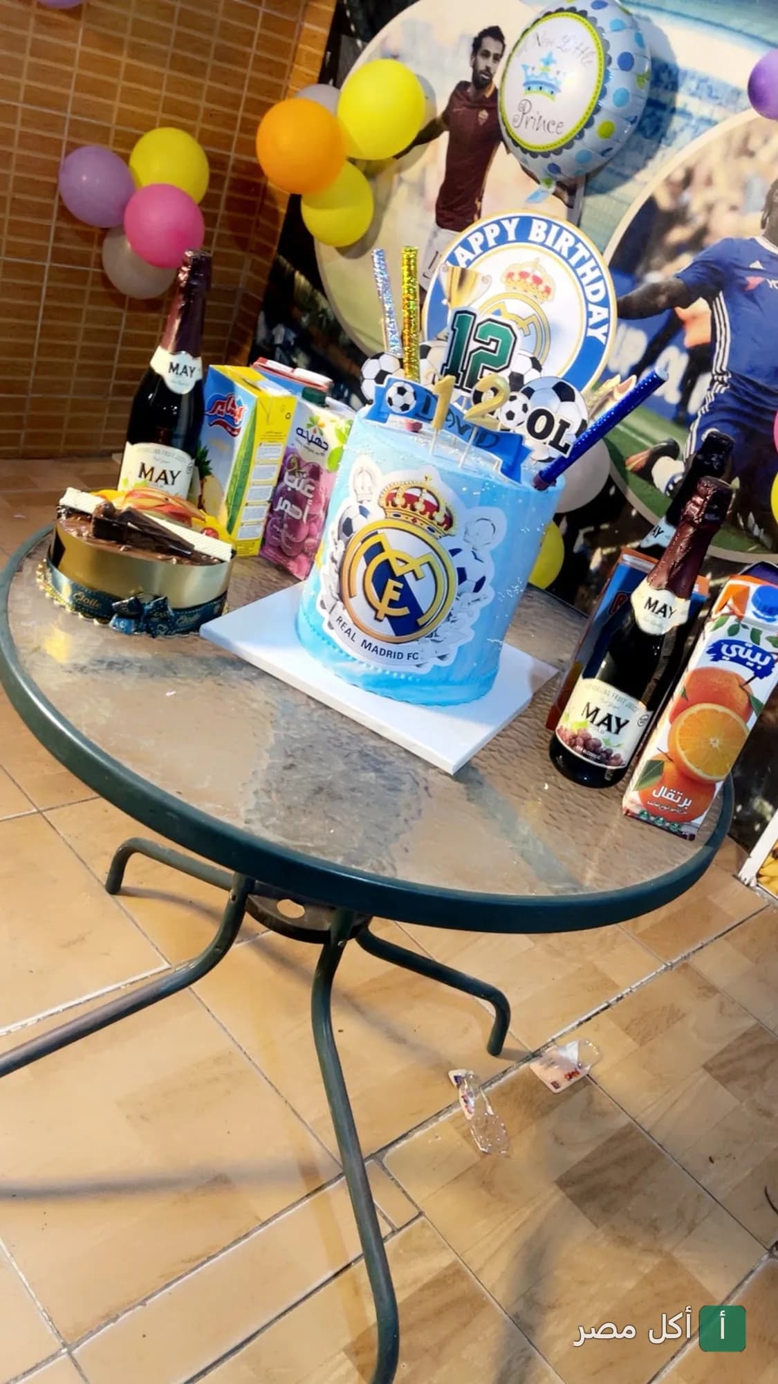 تورتة عيد ميلاد بطابع ريال مدريد وعصائر ومشروبات على طاولة في مطعم بليسينج النيجيري بالمقطم.