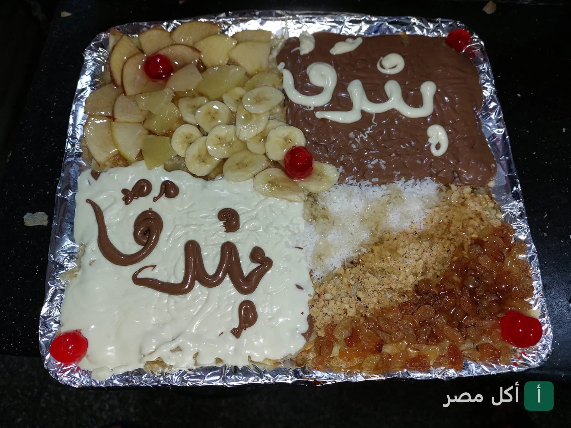 بيتزا حلوة من بيتزا بندق مقسمة لأربع أجزاء عليها فواكه وشوكولاتة ومكسرات