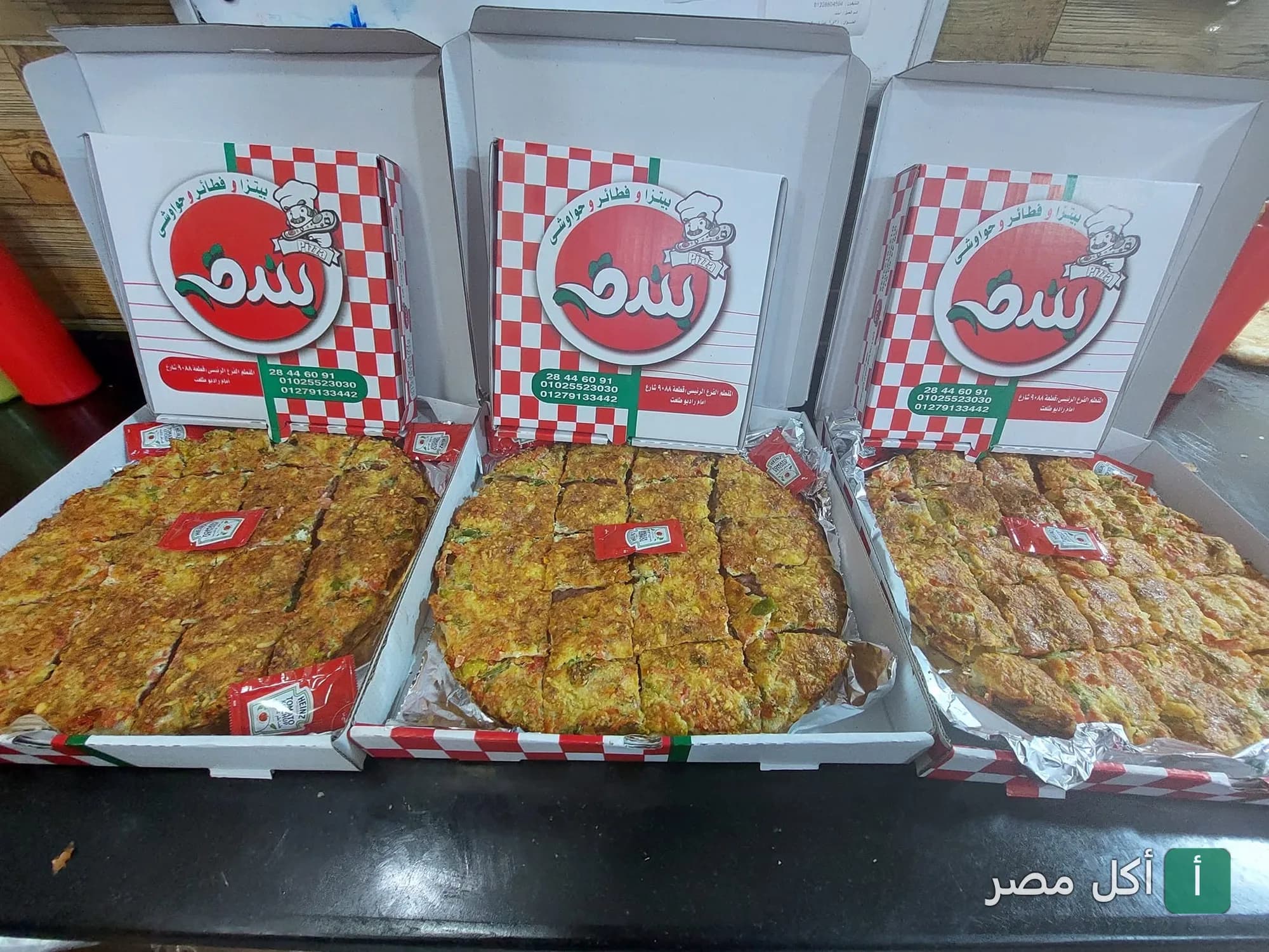 ثلاث علب بيتزا من بيتزا بندق بالخليفة مفتوحة وتظهر بداخلها فطائر مقطعة.