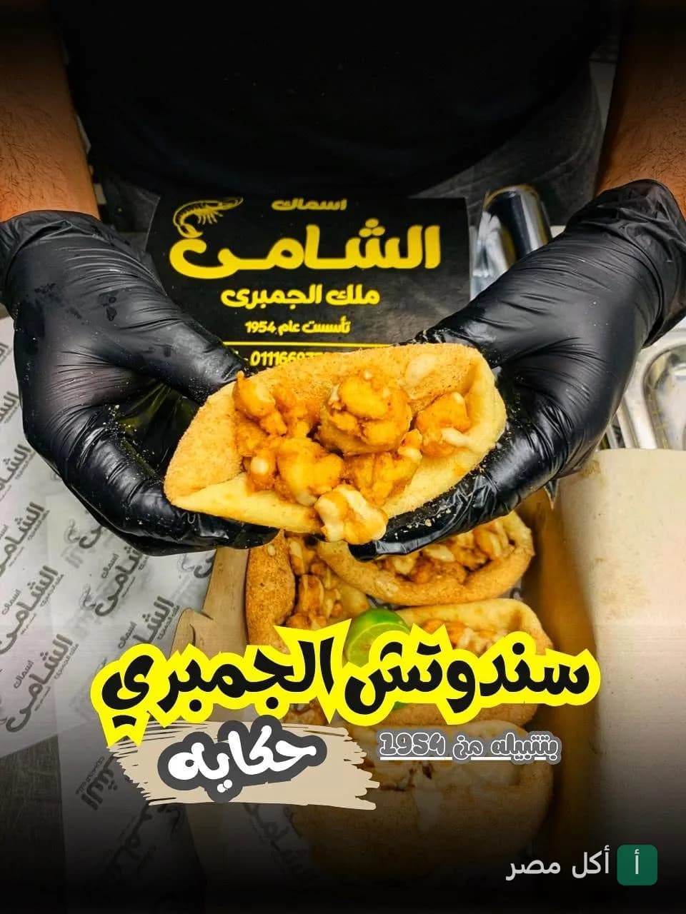شيف يرتدي قفازات سوداء يقدم ساندوتش جمبري طازج في مطعم الشامي للأسماك.