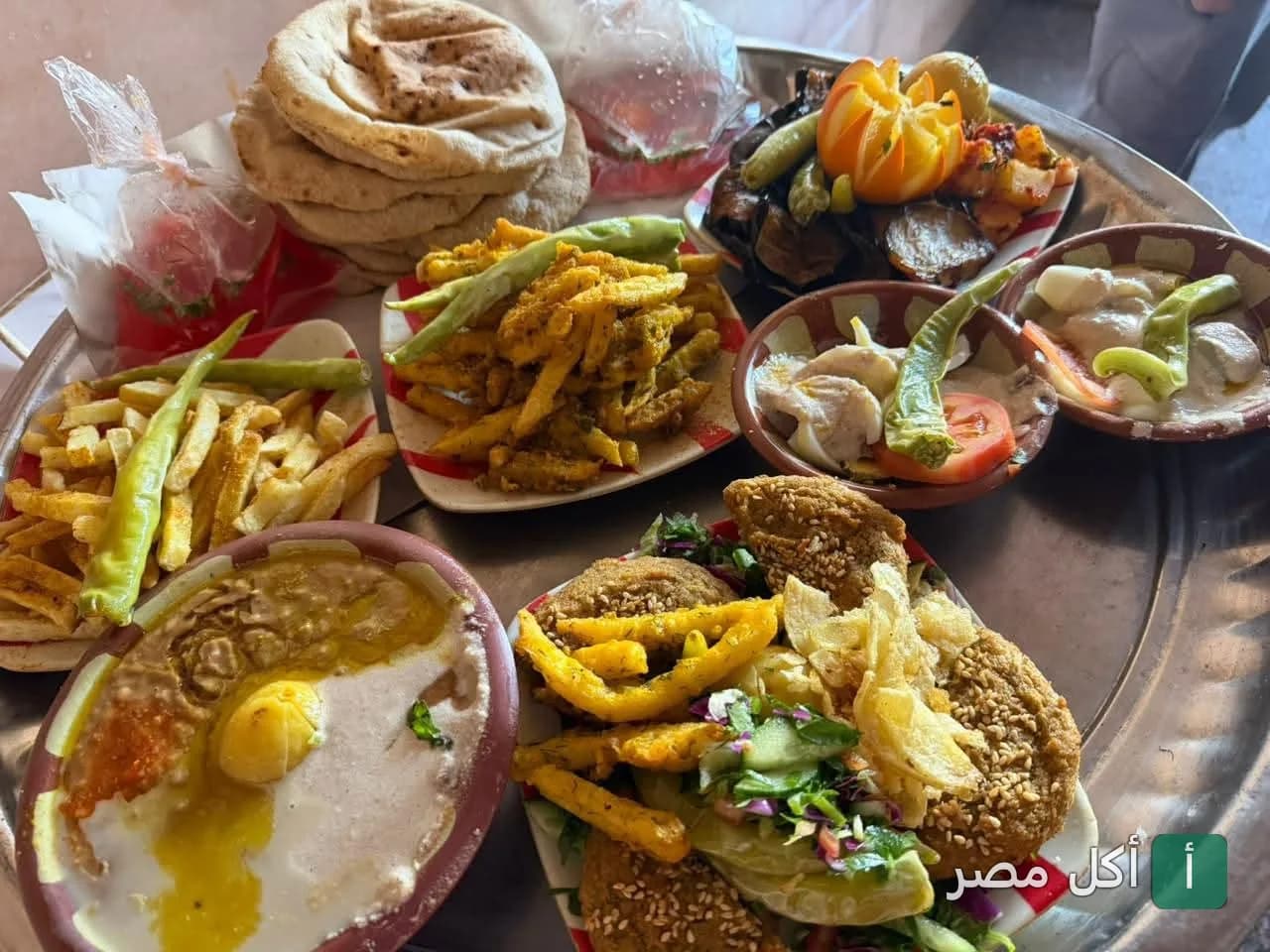 صينية فطور مصري شعبي متنوعة تضم الفول، الطعمية، البطاطس المقلية، والخبز البلدي في مطعم الملك بالخليفة.