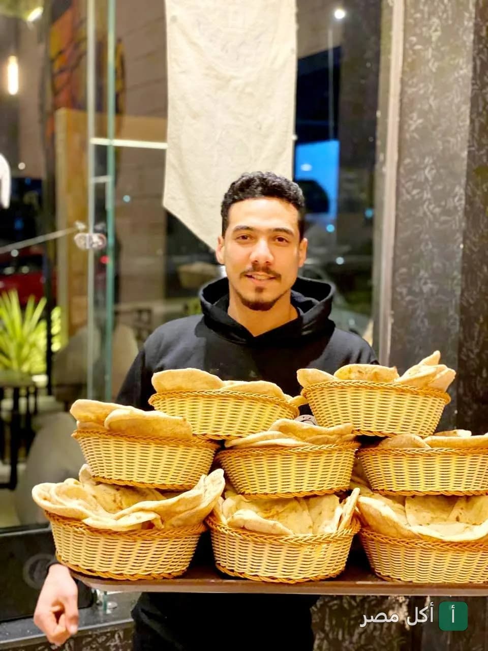 موظف في بيكاسو كافيه بالخليفة يحمل سلالاً مليئة بالخبز الطازج.
