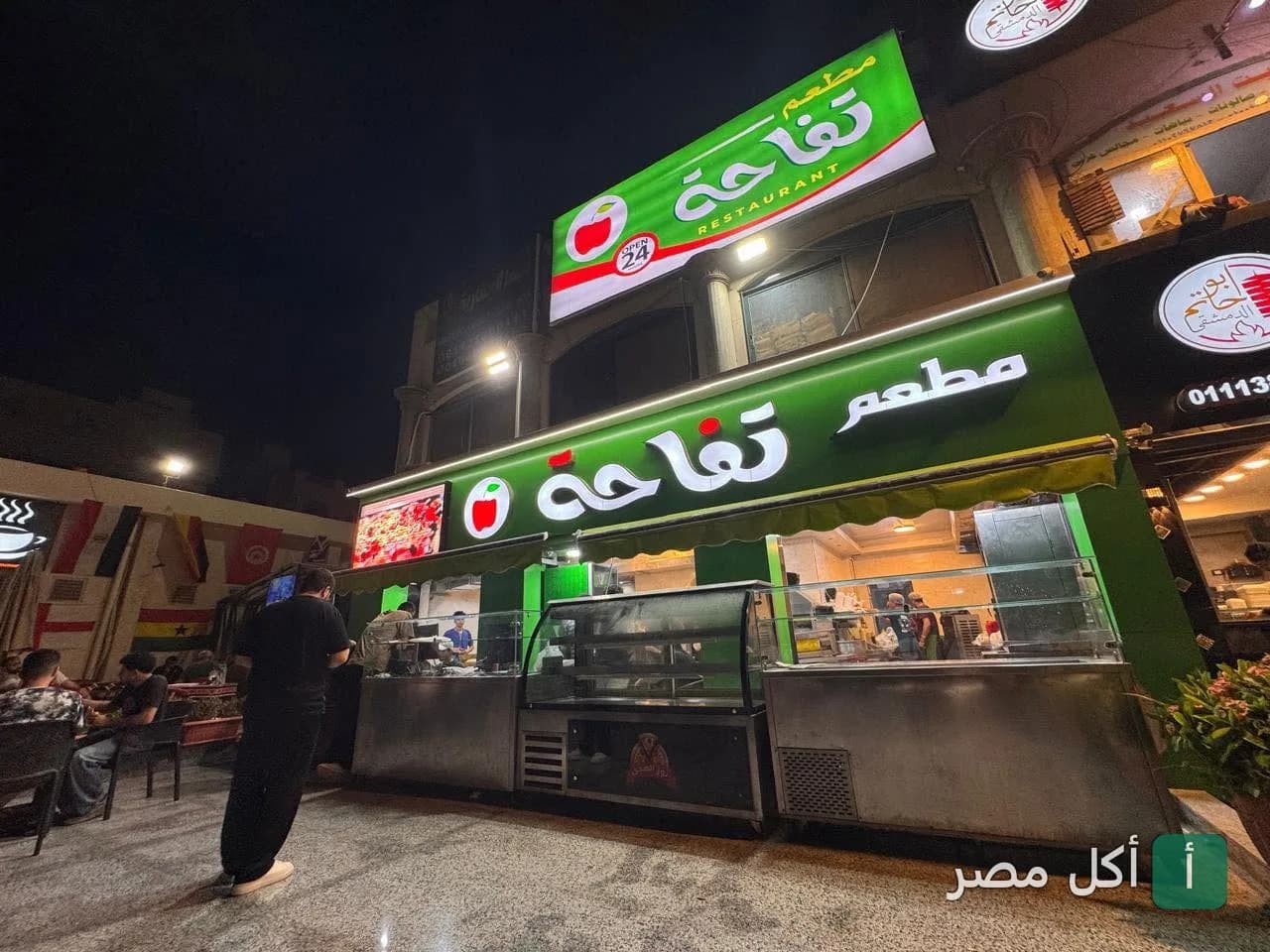 واجهة مطعم تفاحة في 6 أكتوبر ليلاً مع لافتة خضراء مضيئة.
