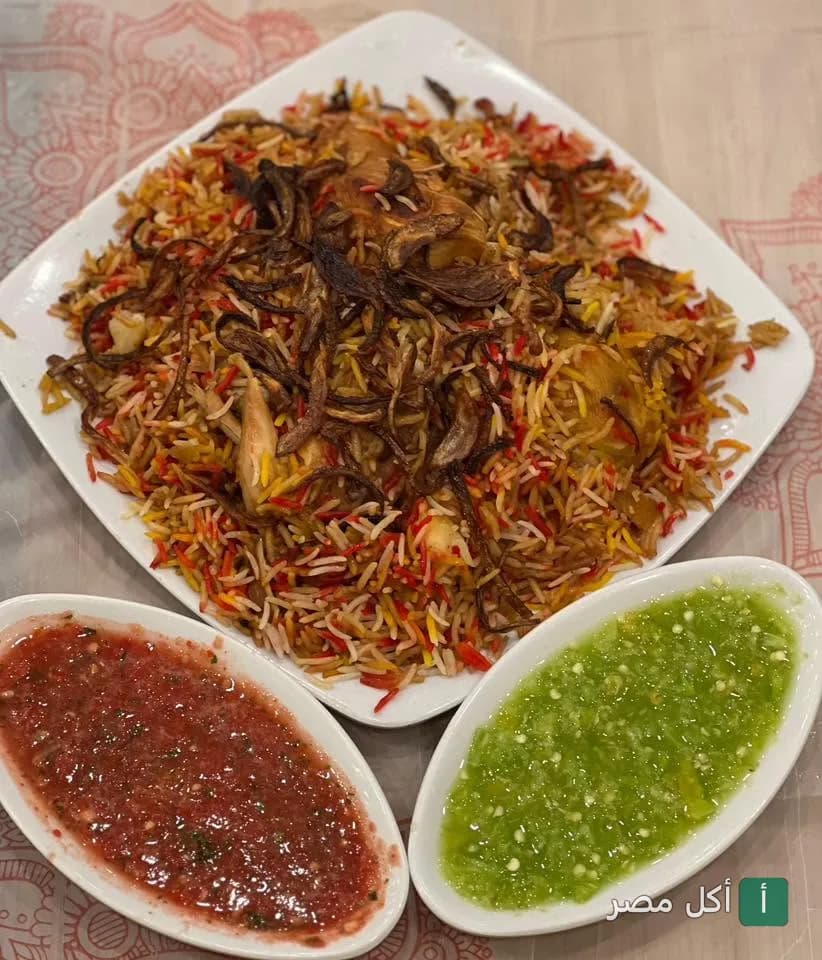 طبق أرز مندي مع الدجاج والبصل المحمر يقدم مع صلصة الدقوس الحمراء والخضراء في مطعم واحة عدن بمدينة 6 أكتوبر.