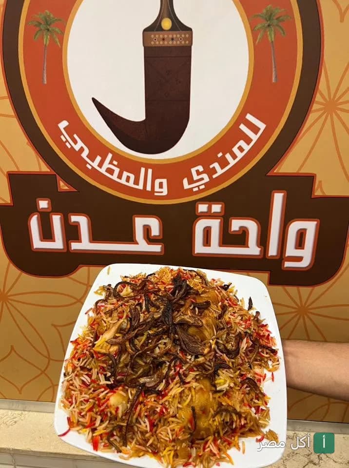 طبق أرز بالمندي والمظبي من مطعم واحة عدن في 6 أكتوبر أمام شعار المطعم.
