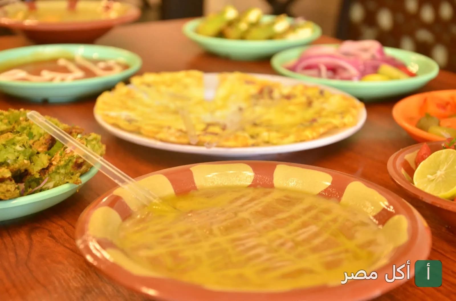 سفرة فطور مصري تقليدي تحتوي على أطباق الفول والبيض والمقبلات في مطعم فول نور بمدينة 6 أكتوبر.