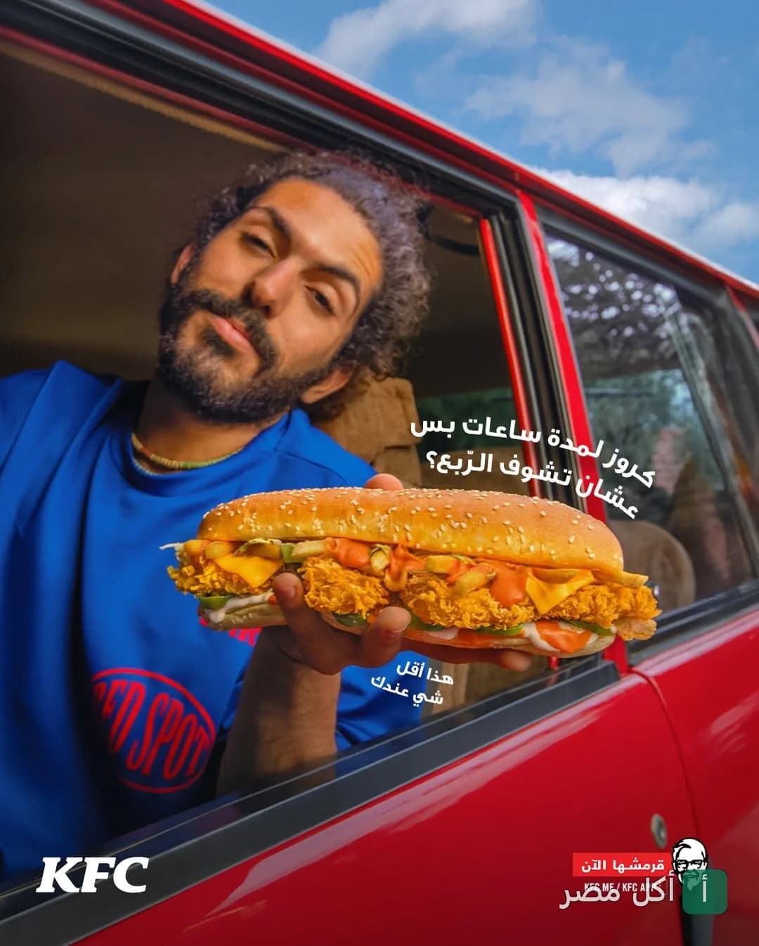 شاب يخرج من نافذة سيارة حمراء حاملاً ساندوتش دجاج مقرمش من كنتاكي في 6 أكتوبر.