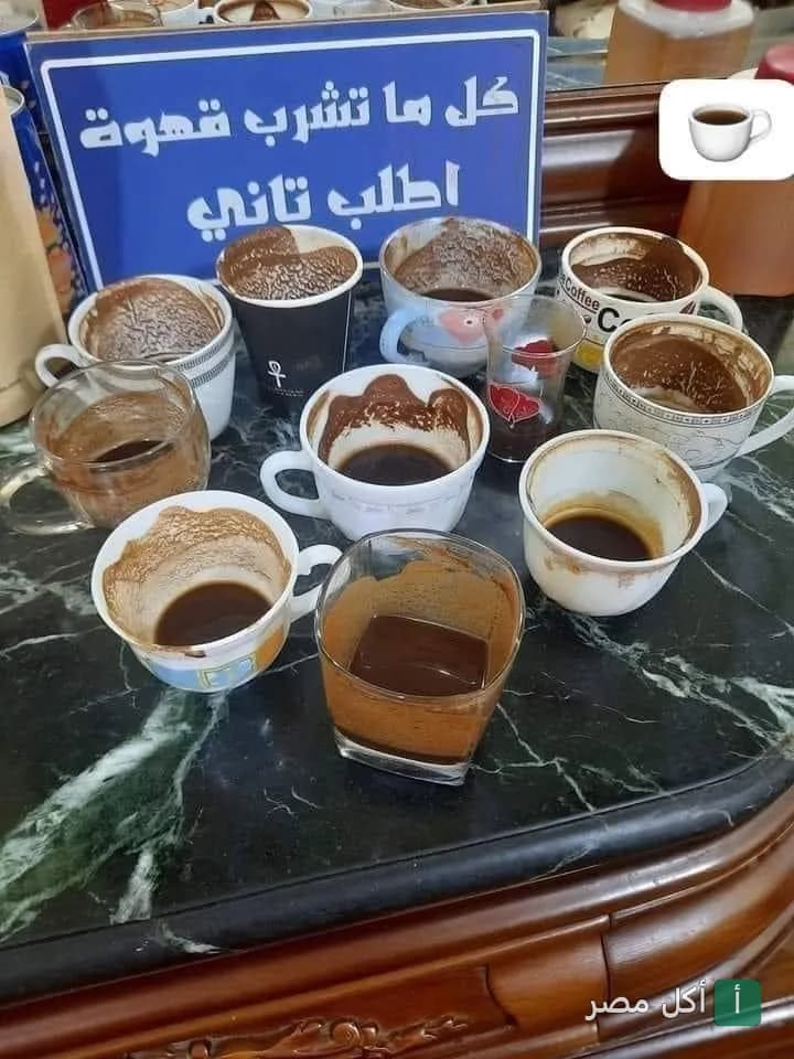 مجموعة من فناجين القهوة الفارغة بعد شربها في كافيه بن ادريس بالعجوزة، مع لافتة مكتوب عليها كل ما تشرب قهوة اطلب تاني.