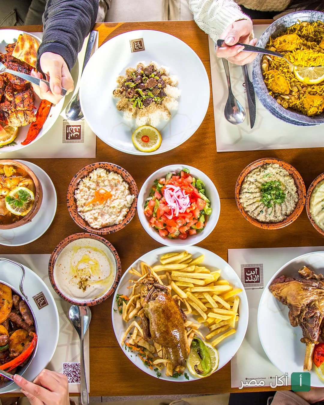 مائدة طعام متنوعة من مطعم إبن البلد تضم أطباق مشاوي مصرية، أرز، مقبلات، وسلطات.