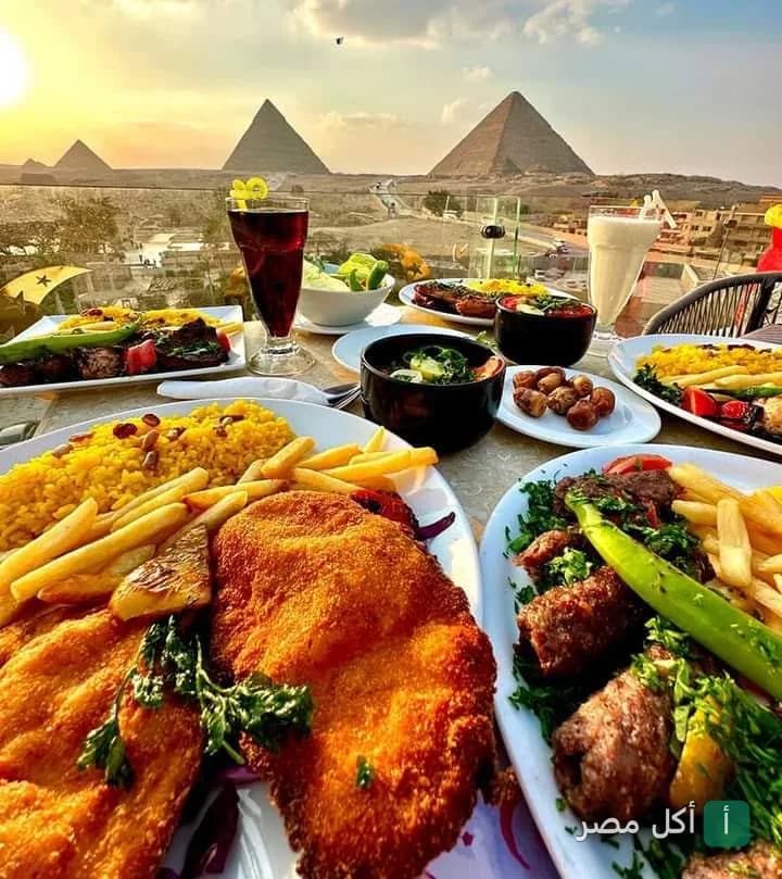 مائدة طعام متنوعة من المشويات والأطباق الجانبية مع إطلالة بانورامية على أهرامات الجيزة من هيفين لاونج.