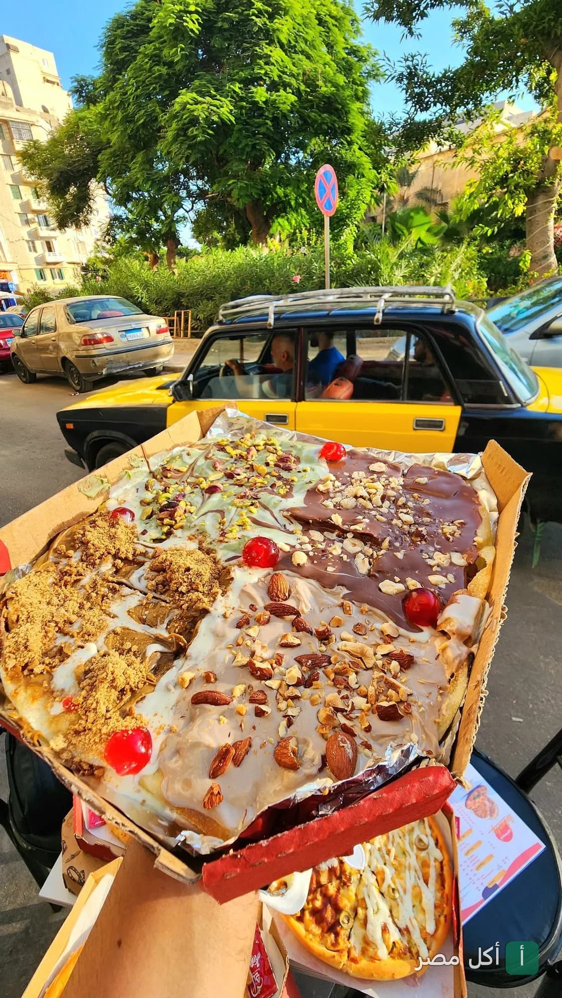 علبة كريب حلو متنوع الإضافات من مطعم تيبستي الكوربة في شارع حيوي.