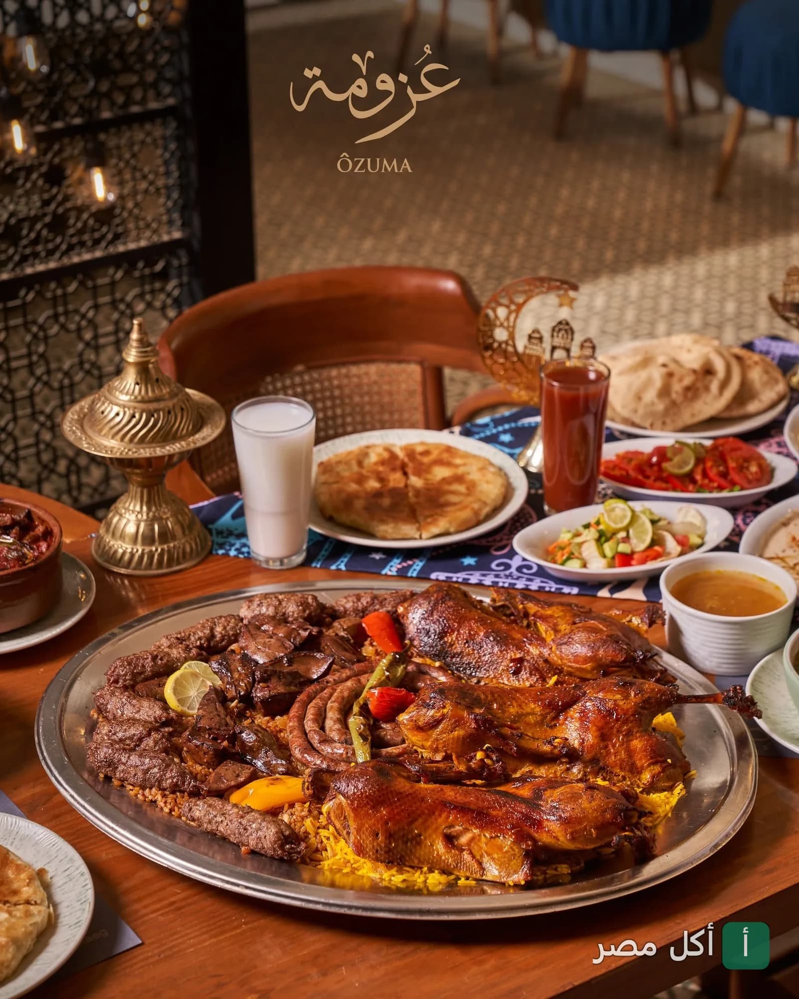 صينية عزومة الكبيرة تضم بط مشوي، كفتة، وسجق على أرز، مع مقبلات ومشروبات في مطعم عزومة.