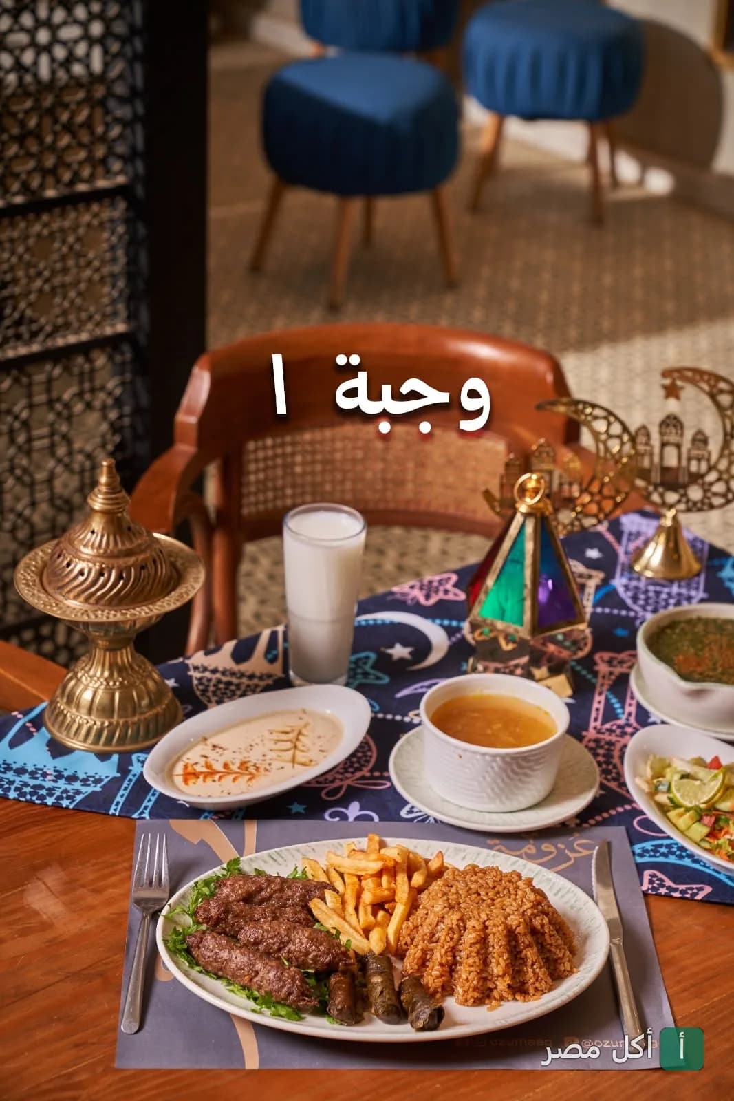 وجبة عزومة رمضانية تحتوي على كفتة وأرز وبطاطس محمرة ومقبلات على مائدة مزينة بفانوس.