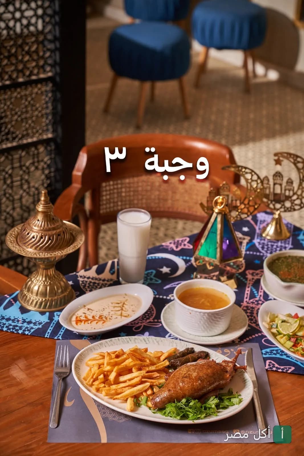 وجبة ٣ من مطعم عزومة في الأهرام، تتضمن طبق رئيسي مع بطاطس محمرة ومقبلات على مائدة رمضانية مزينة.
