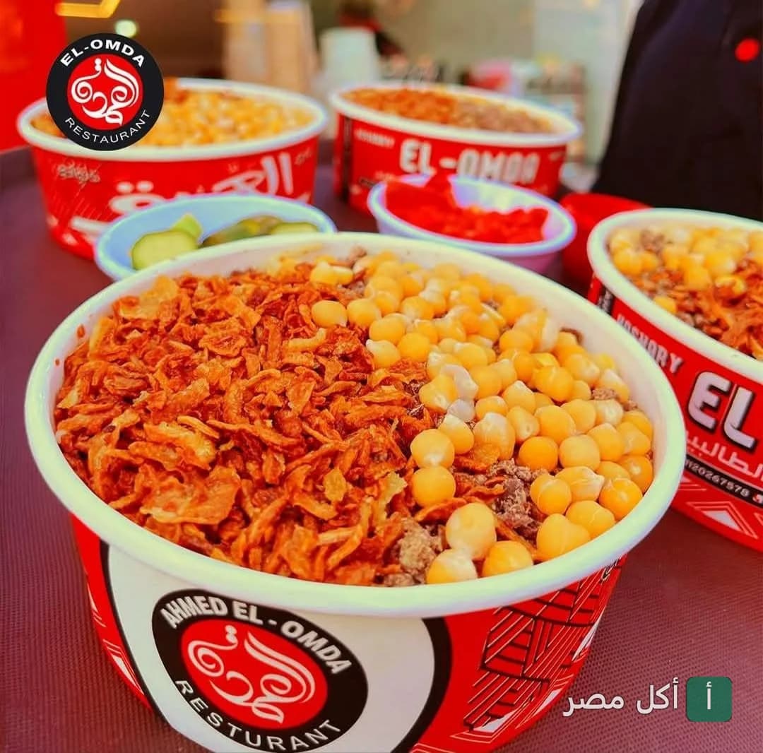أطباق كشري مصري في عبوات حمراء تحمل شعار مطعم كشري العمدة.