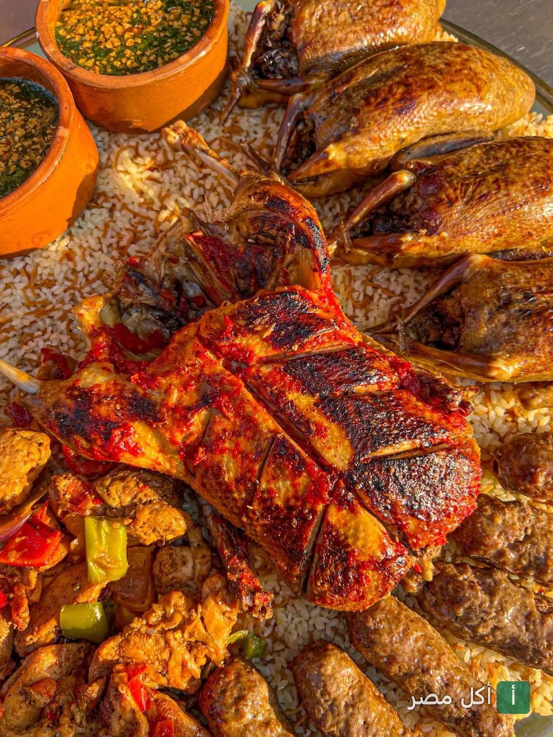 طبق مشويات مصري متنوع يضم حمام محشي وكفتة وقطع دجاج على أرز في مطعم شيخ البلد ببولاق الدكرور.