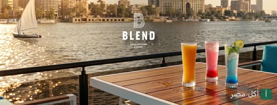 صورة غلاف مطعم بليند تظهر مشروبات ملونة على طاولة خشبية مطلة على النيل مع مركب شراعي في الخلفية.