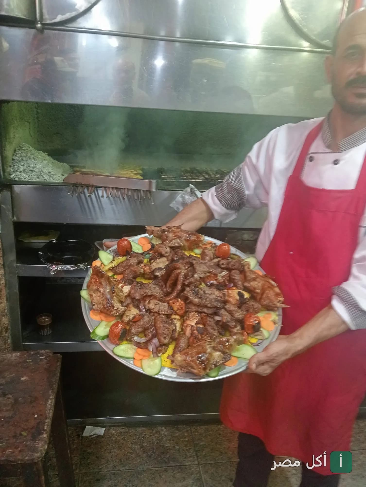شيف في كبابجي الشحات ببولاق الدكرور يقدم صينية مشويات مشكلة طازجة من على الشواية.