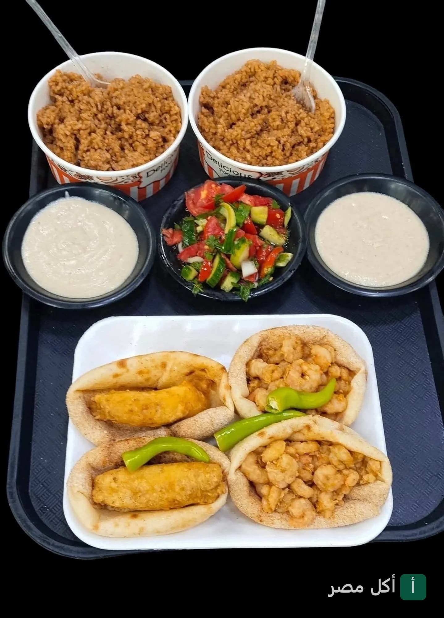 صينية تقديم من كبدة ومخ اولاد مهران ببولاق الدكرور تحتوي على ساندوتشات وأطباق أرز وسلطة وطحينة.