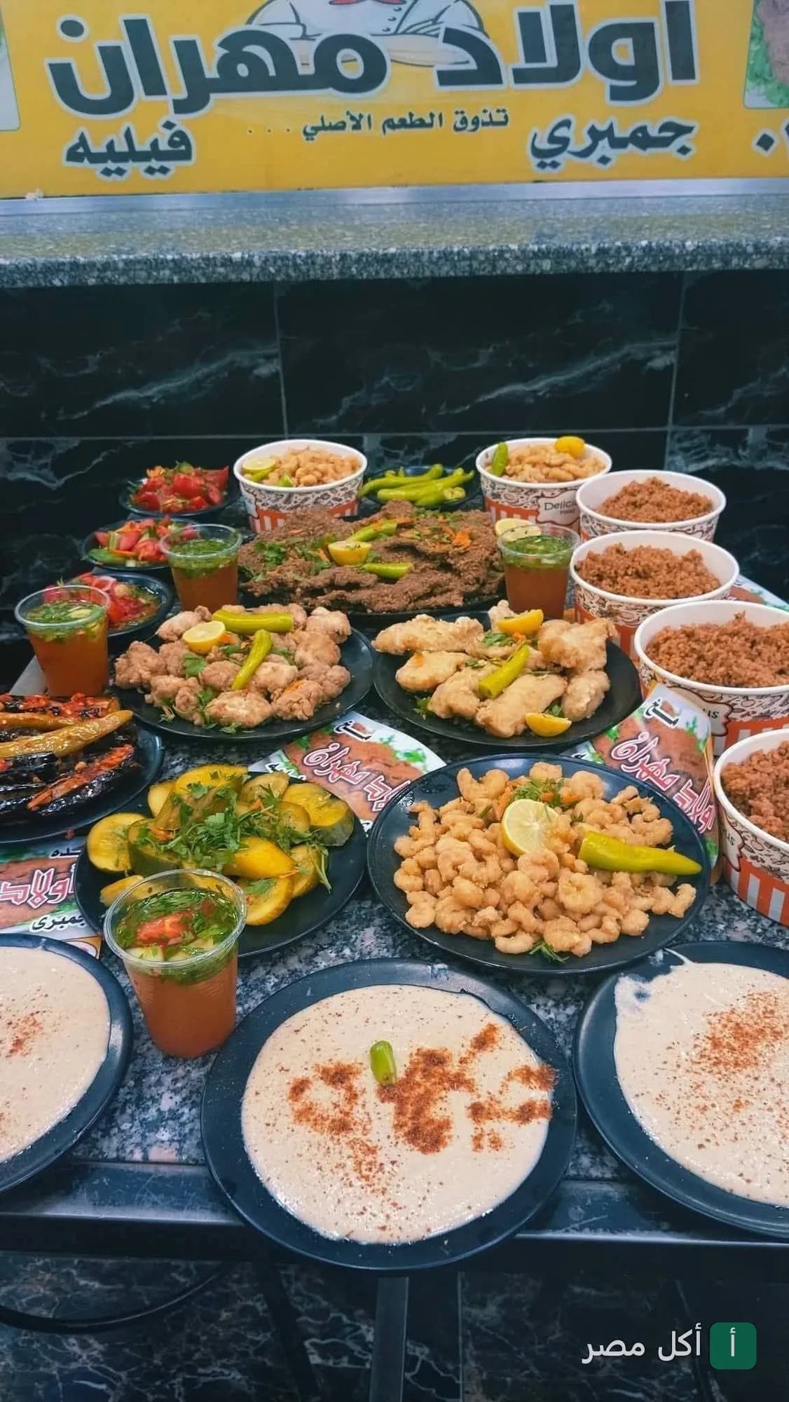 تشكيلة متنوعة من أطباق كبدة ومخ أولاد مهران في بولاق الدكرور، تضم أطباق مقليات وسلطات.