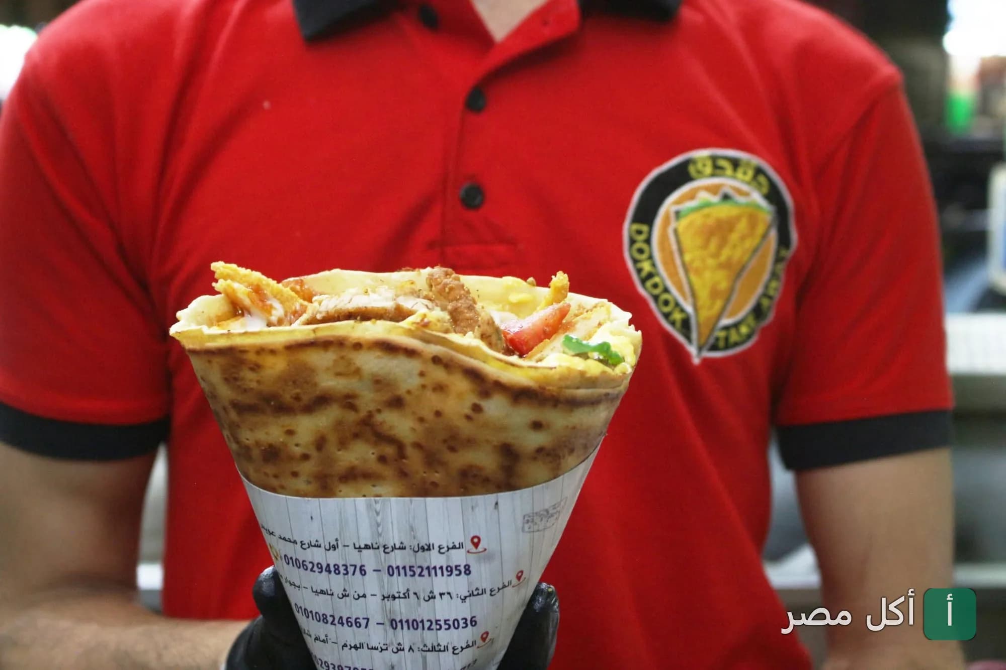 موظف يرتدي زي تيك أواي كريب دقدق الأحمر ويحمل كريب محشو في بولاق الدكرور