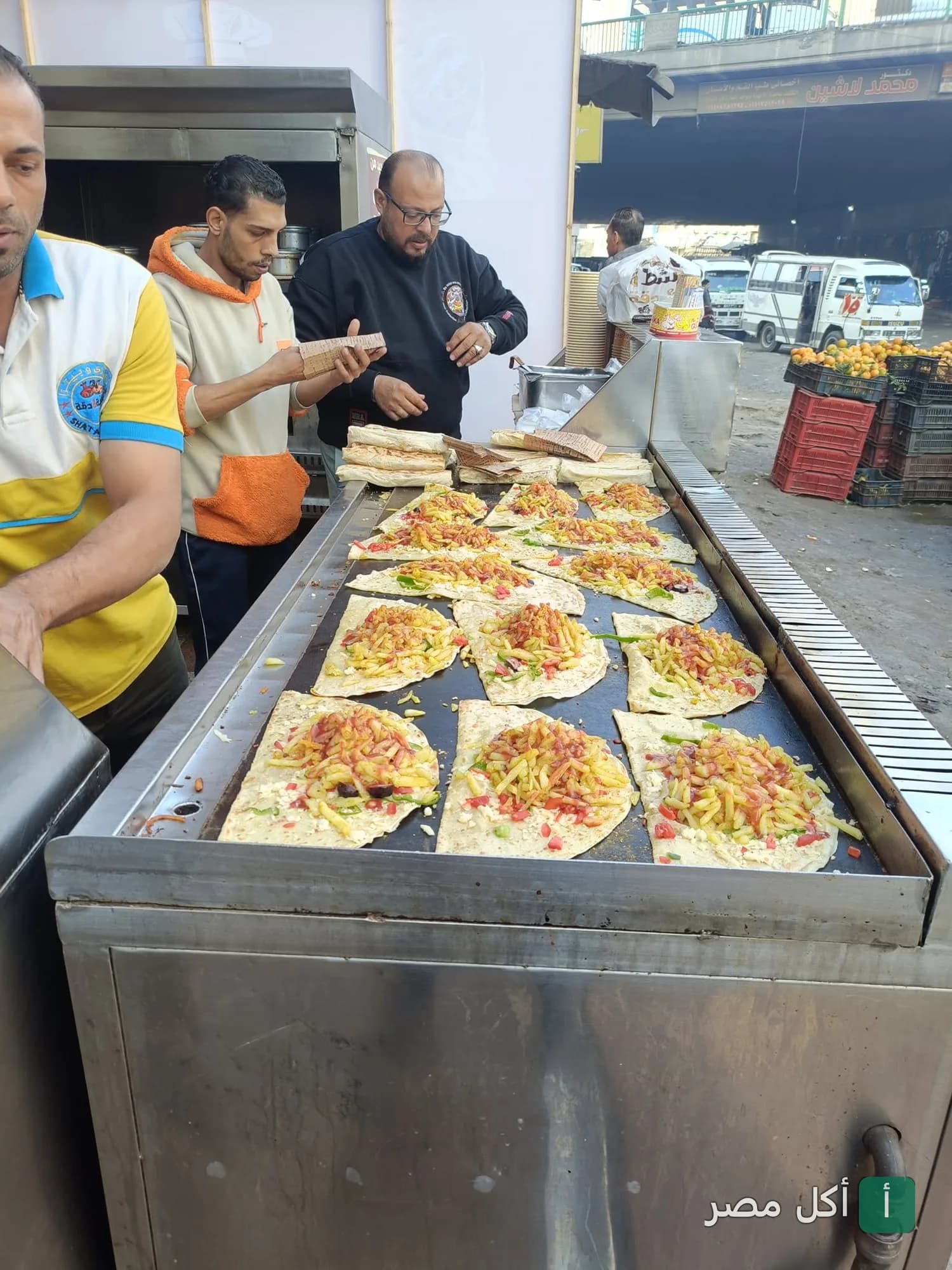 طباخون يحضرون الساندوتشات على صاج كبير في مطعم شطة ببولاق الدكرور.