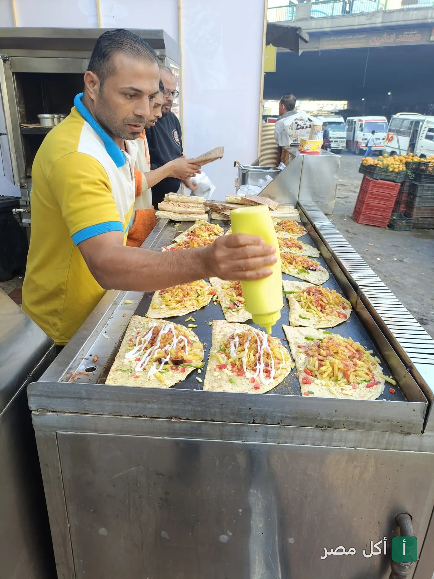 طباخ في مطعم شطة ببولاق الدكرور يضيف الصوص على الساندوتشات على الصاج.
