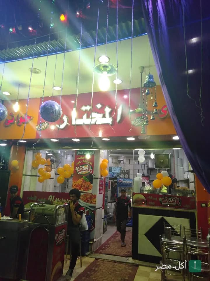 واجهة مطعم كشري المختار في بولاق الدكرور مع لافتة مضيئة وديكورات احتفالية
