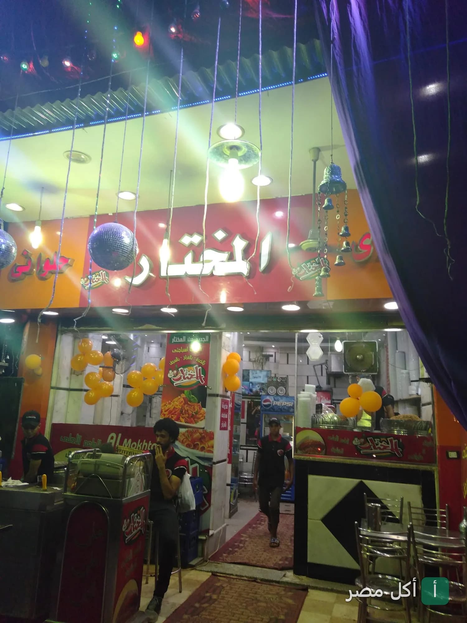 واجهة مطعم كشري المختار في بولاق الدكرور مع ديكورات مضيئة وأجواء داخلية