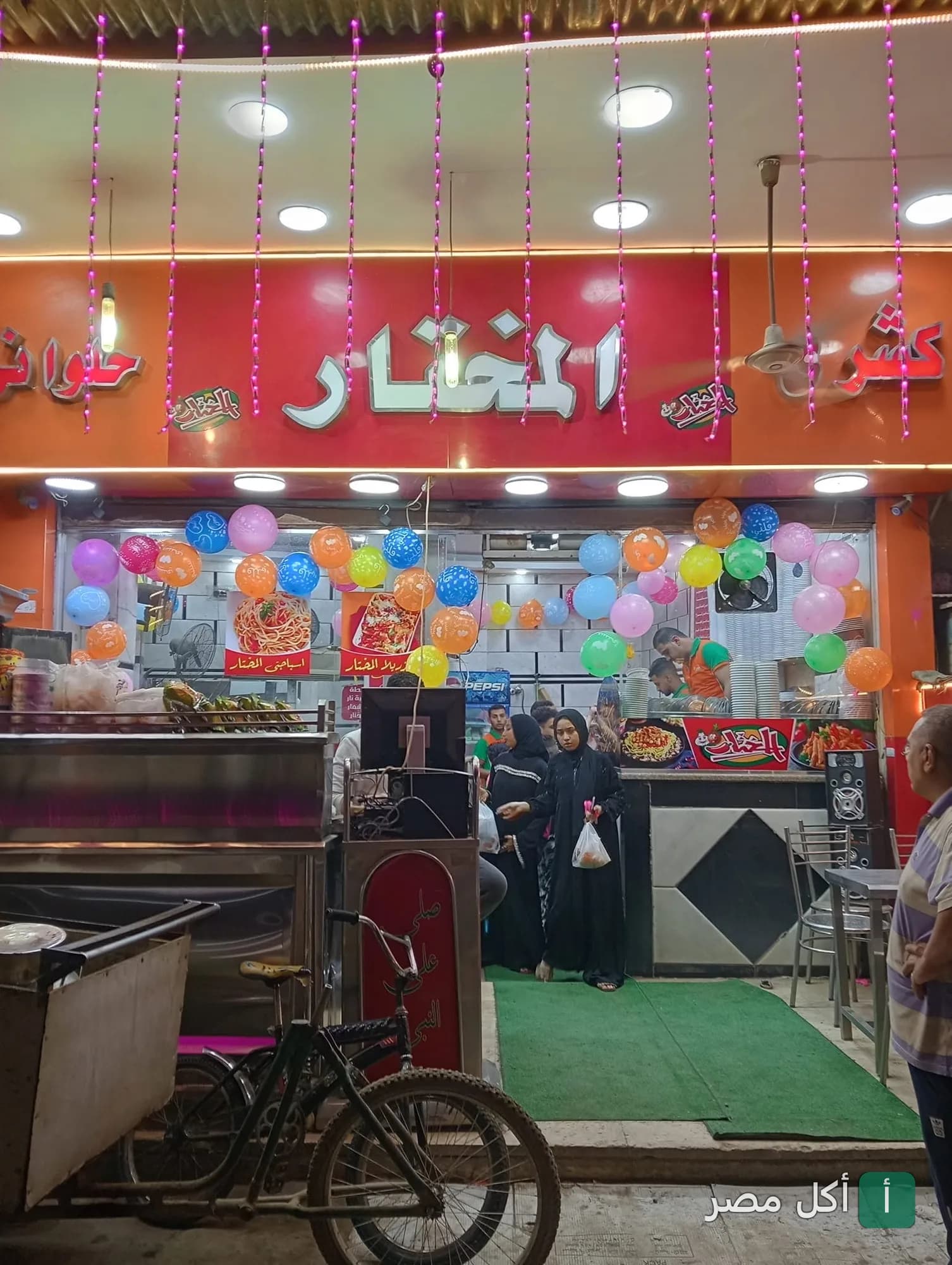 واجهة مطعم كشري المختار في بولاق الدكرور مزينة بالبالونات الملونة.