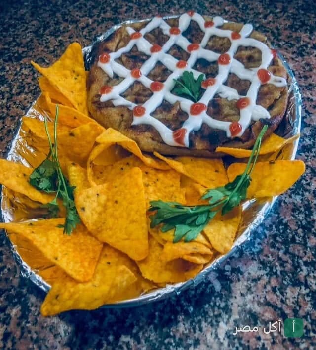 طبق حواوشي مزين بصوص الطحينة والكاتشب مع رقائق الناتشوز في مطعم كبابجي البركة بالعمرانية بالجيزة.
