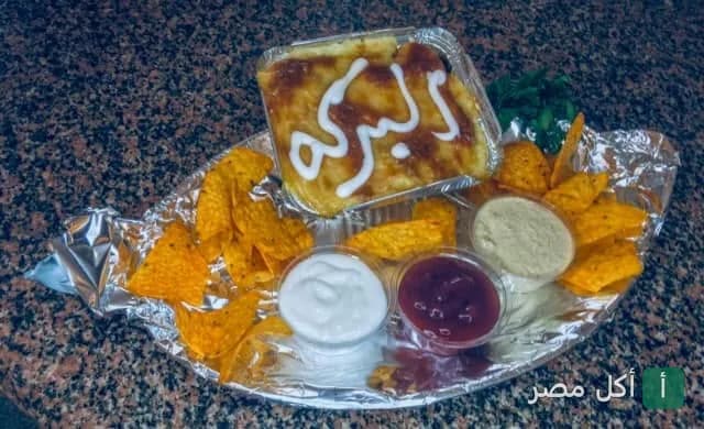 وجبة من كبابجي البركة في العمرانية بالجيزة تتضمن طبقاً مكتوباً عليه اسم المطعم مع رقائق التورتيلا وثلاثة أنواع من الصوص.
