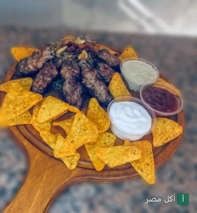طبق مشويات كبابجي البركة في العمرانية بالجيزة مع رقائق الناتشوز وثلاث أنواع من الصوصات.
