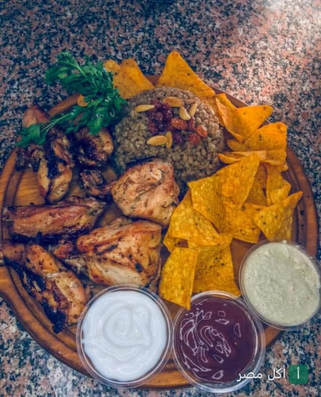 طبق مشويات من كبابجي البركة في العمرانية بالجيزة يضم قطع دجاج مشوي مع أرز بالخلطة ورقائق مقرمشة وصوصات