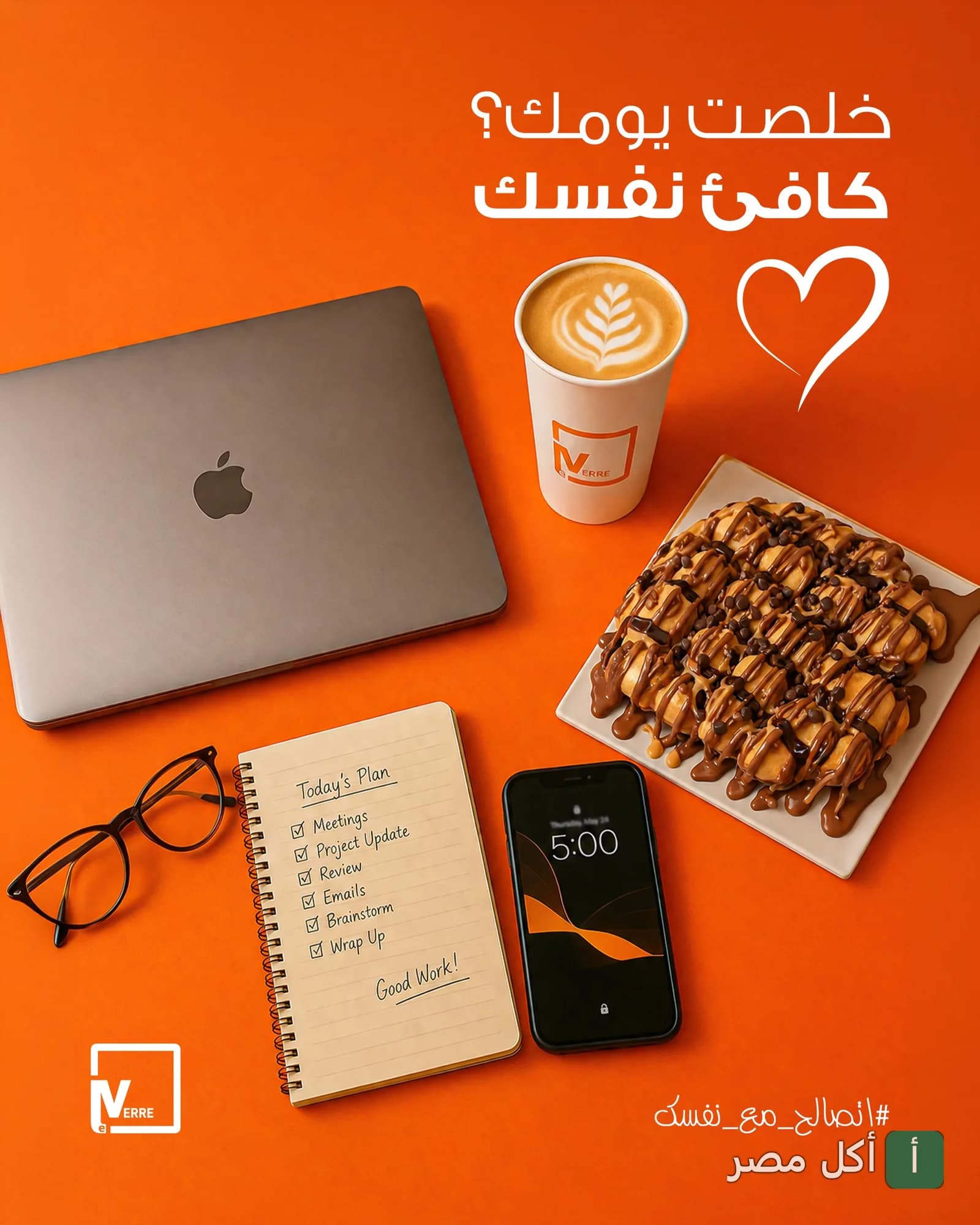 طبق حلويات مع كوب قهوة بجانب لابتوب ونوت بوك على مكتب في مطعم لافيرا بالعمرانية الغربية، الجيزة.